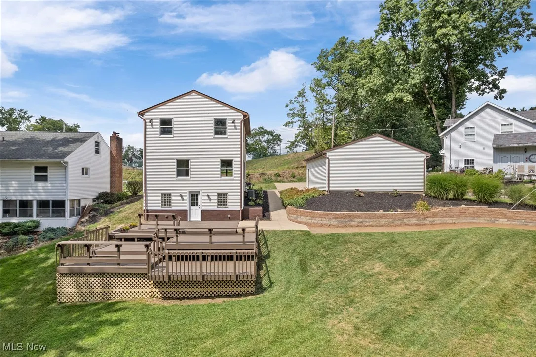 Rear view of house featuring a wooden deck and a lawn