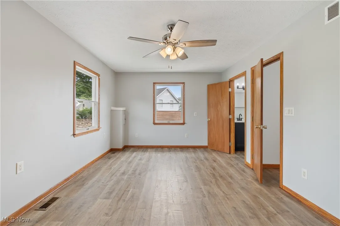Spare room featuring light wood-style flooring, healthy amount of natural light, a textured ceiling, and a ceiling fan