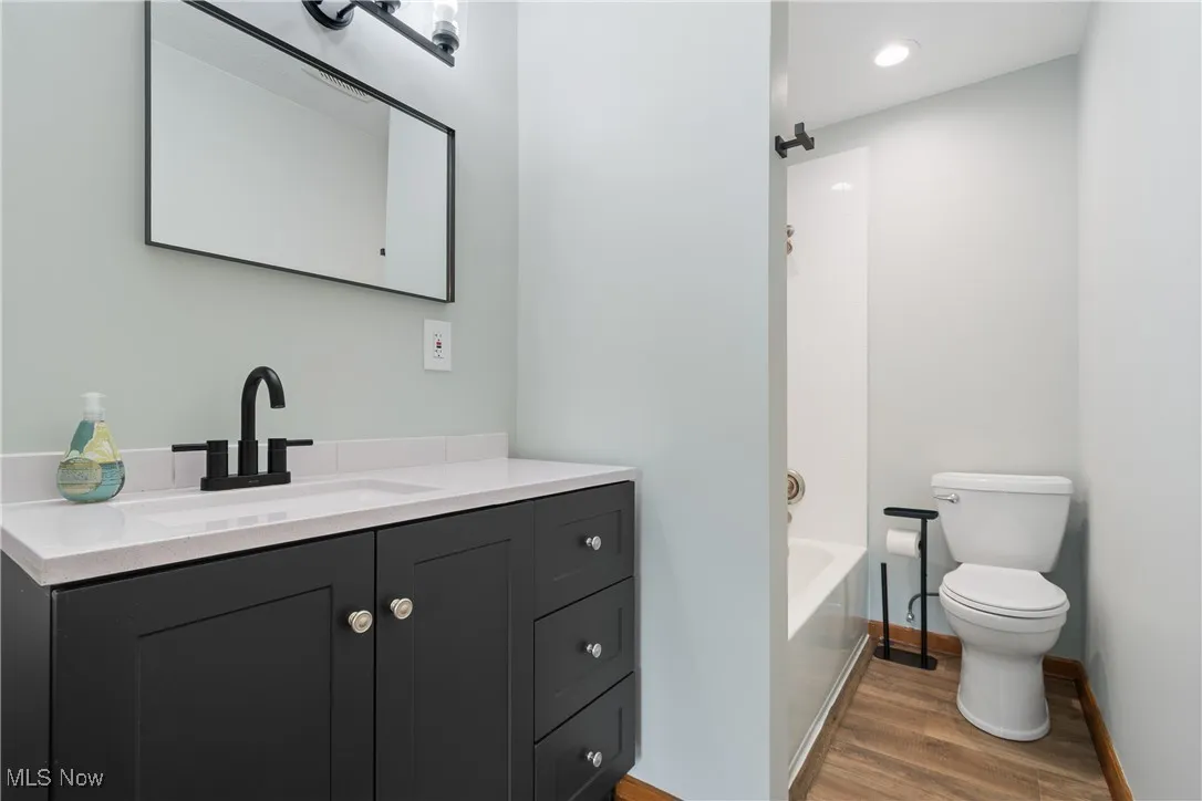 Full bath featuring vanity, wood finished floors, and washtub / shower combination