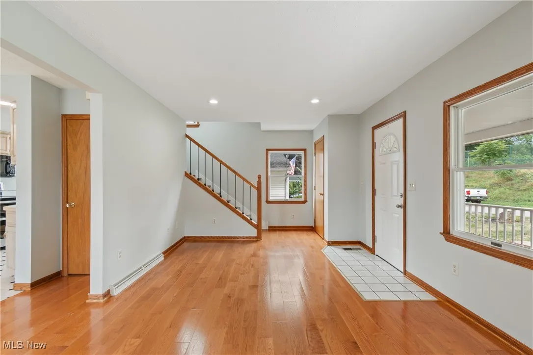 Foyer featuring baseboard heating, light wood finished floors, healthy amount of natural light, and recessed lighting