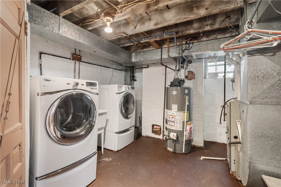 Laundry room with concrete flooring, gas water heater, and heating unit