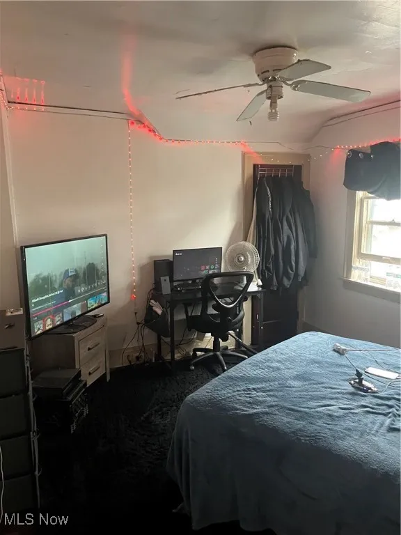 Bedroom featuring ceiling fan and dark carpet