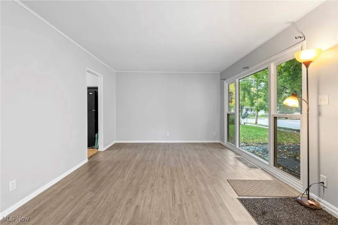 Unfurnished room with light wood finished floors and ornamental molding