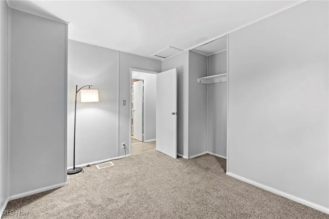 Unfurnished bedroom with carpet and attic access