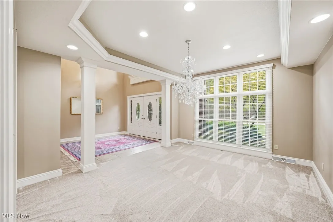 Foyer entrance and Formal dining room featuring ornate columns, light carpet, recessed lighting, ornamental molding, and a chandelier