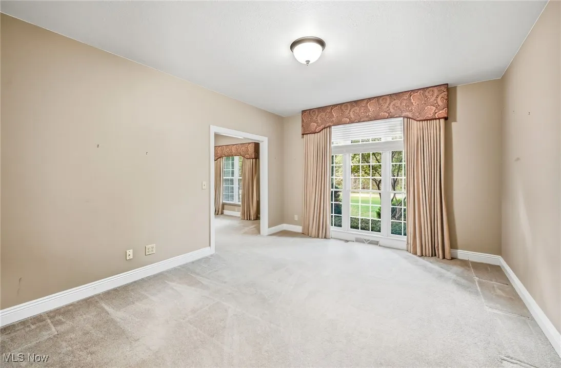 First floor office space/ den with baseboards and light carpet