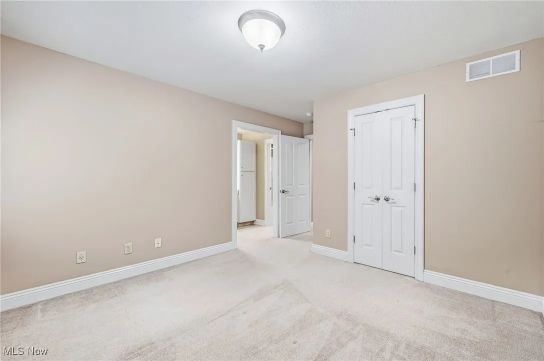 Unfurnished bedroom with light carpet and a walk in closet