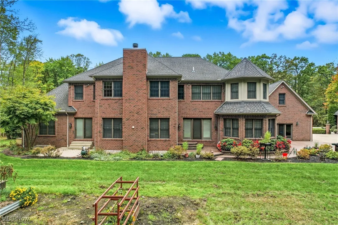 Rear view of house with all brick, a chimney, and garden area