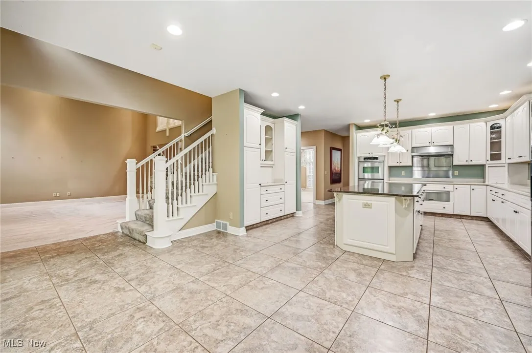 Kitchen featuring glass insert cabinets, a kitchen island, pendant lighting, light tile patterned floors, and recessed lighting