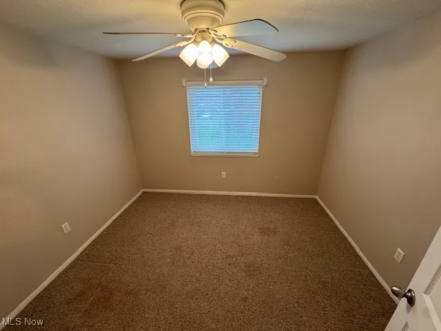 Carpeted empty room featuring baseboards and ceiling fan
