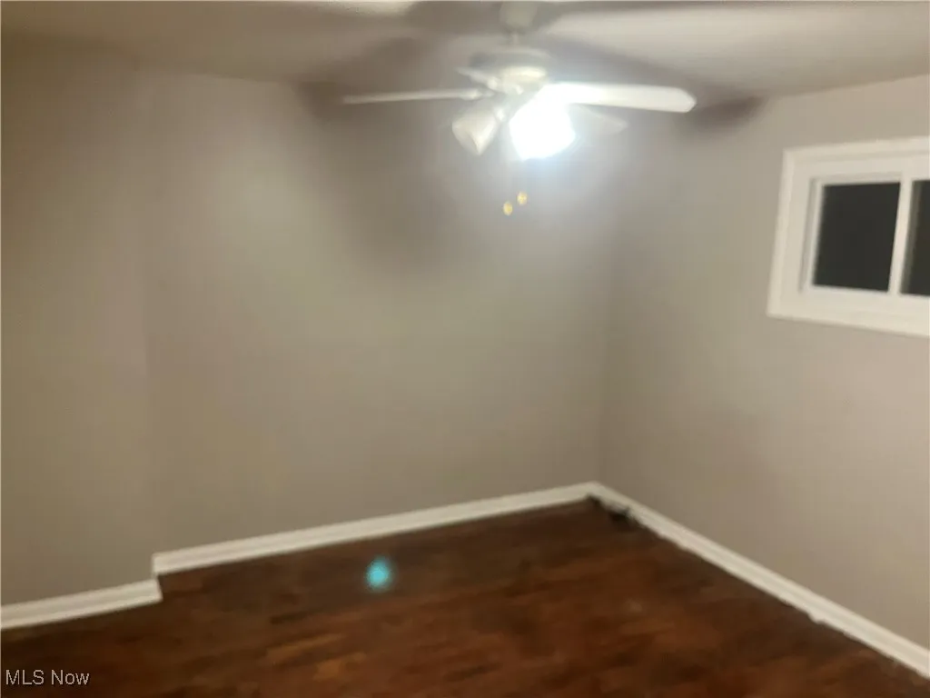 Spare room with dark wood-style flooring and ceiling fan