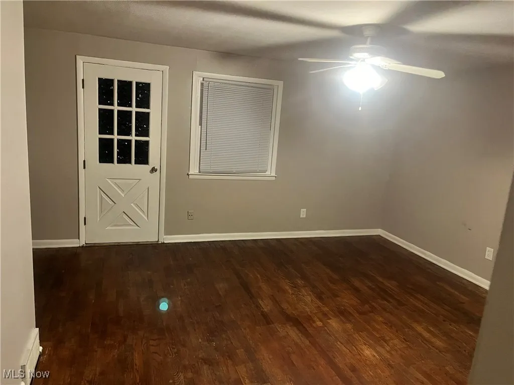 Unfurnished room with dark wood-style flooring and a ceiling fan