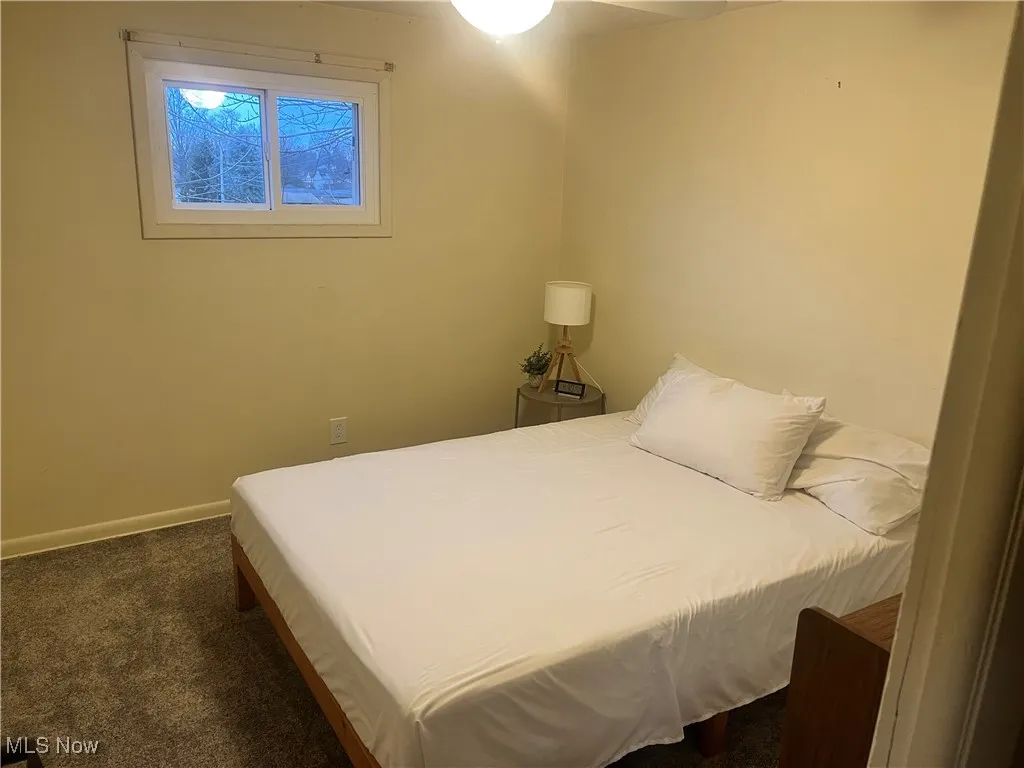 Bedroom with dark colored carpet and baseboards