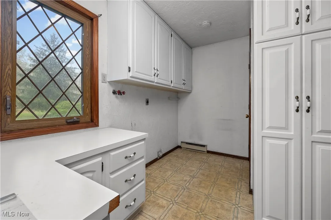 Laundry room with washer hookup, light flooring, electric dryer hookup, a textured ceiling, and cabinet space