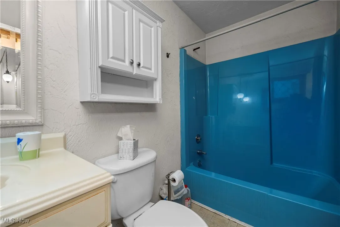 master Bathroom featuring a textured wall, shower / bathtub combination, vanity, and tile patterned flooring