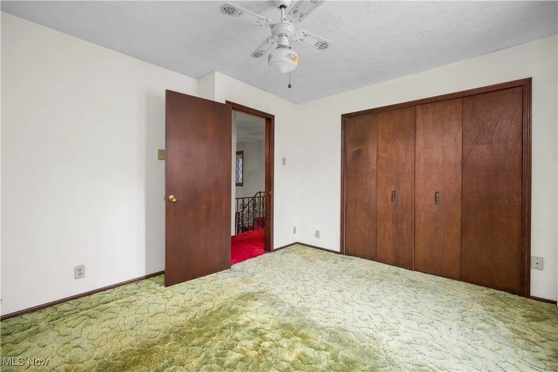 Unfurnished bedroom featuring carpet flooring, a closet, a textured ceiling, and ceiling fan