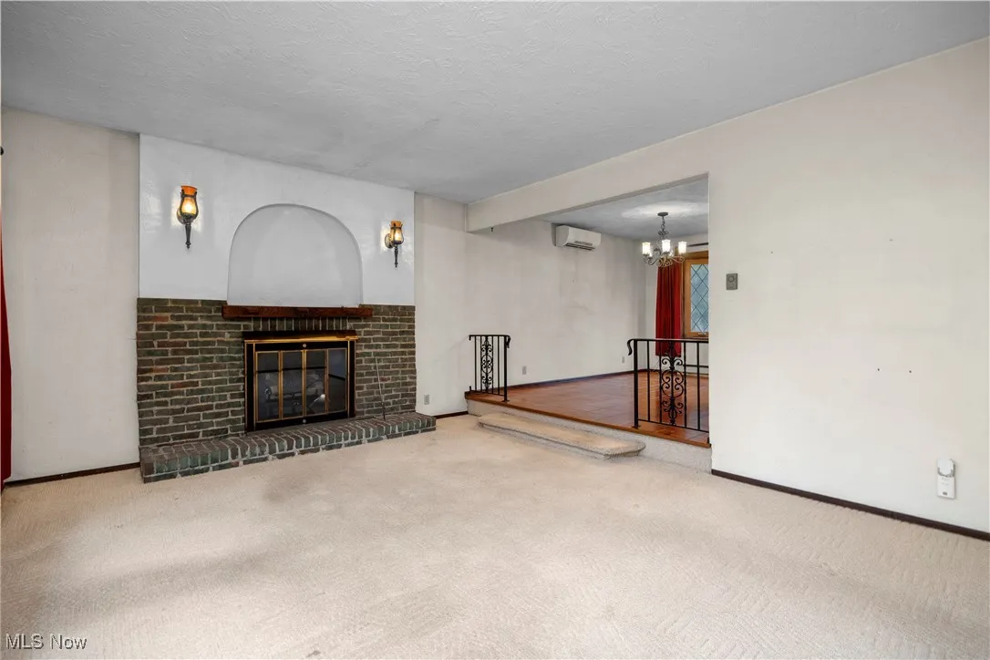 Unfurnished living room featuring a fireplace, carpet flooring, a textured ceiling