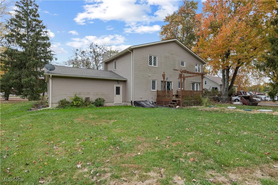 Rear view of property with a deck, a yard, and a chimney