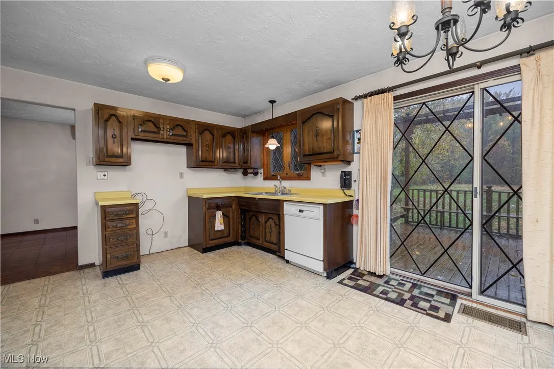 Kitchen featuring countertops, pendant lighting, a textured ceiling, dishwasher, and dark brown cabinetry