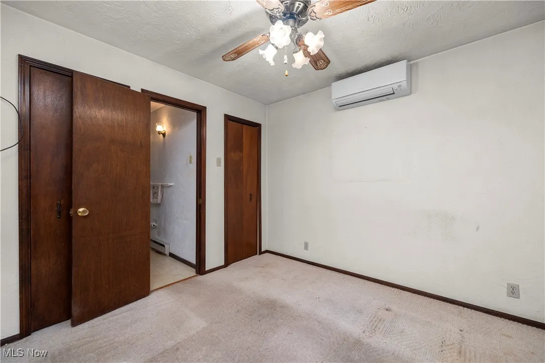 1st floor bedroom with a textured ceiling, light carpet, ceiling fan, ensuite bathroom, and a wall mounted AC