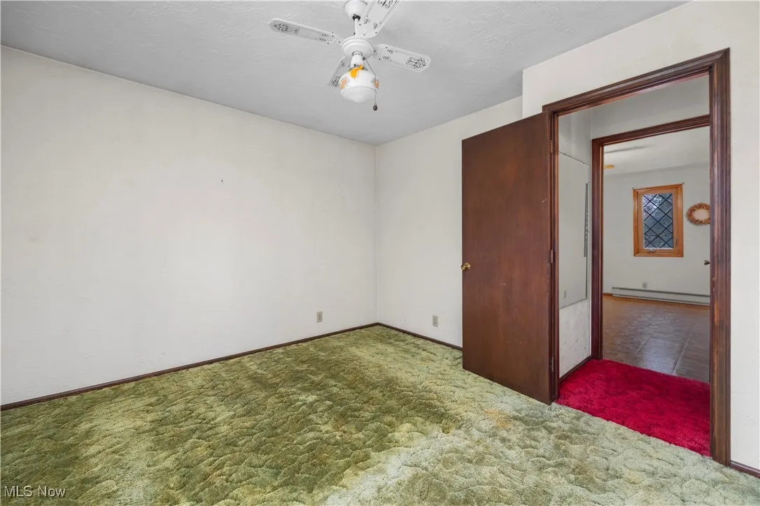 Unfurnished bedroom with carpet flooring, ceiling fan, a baseboard radiator, and a textured ceiling