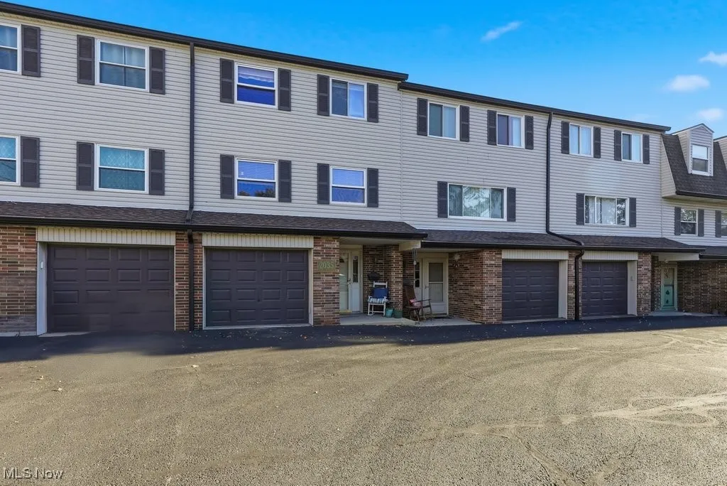 Townhouse featuring vinyl siding, an attached garage, and covered front porch