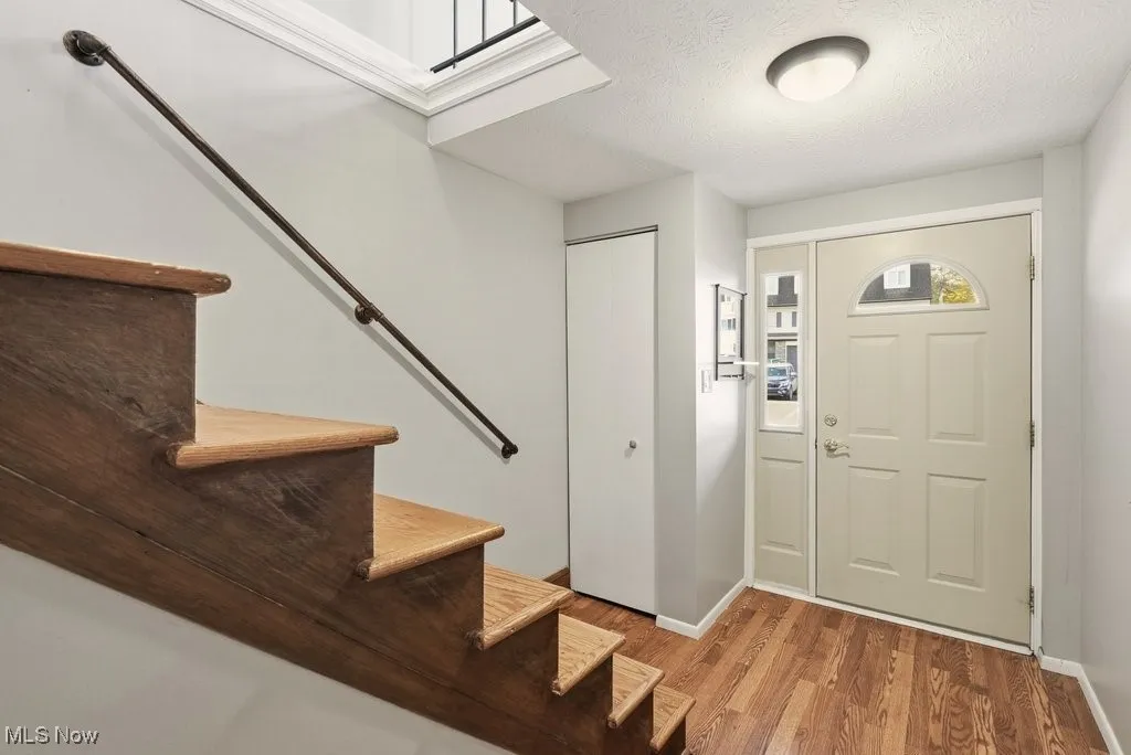 Foyer entrance with a textured ceiling, stairway, and light wood-type flooring