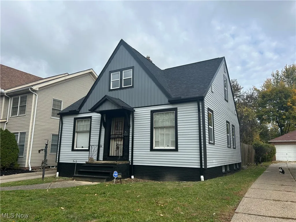 View of front facade featuring a shingled roof, a front lawn, and board and batten siding