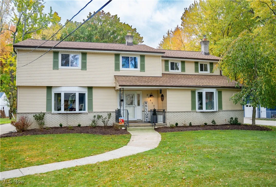 View of front of home with brick siding, a front yard, a chimney, and covered porch