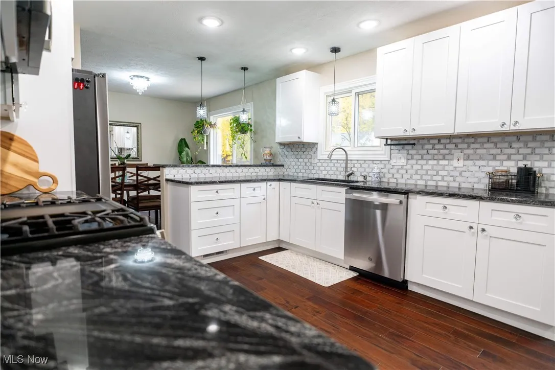Kitchen featuring dark stone countertops, white cabinetry, stainless steel appliances, a peninsula, and recessed lighting