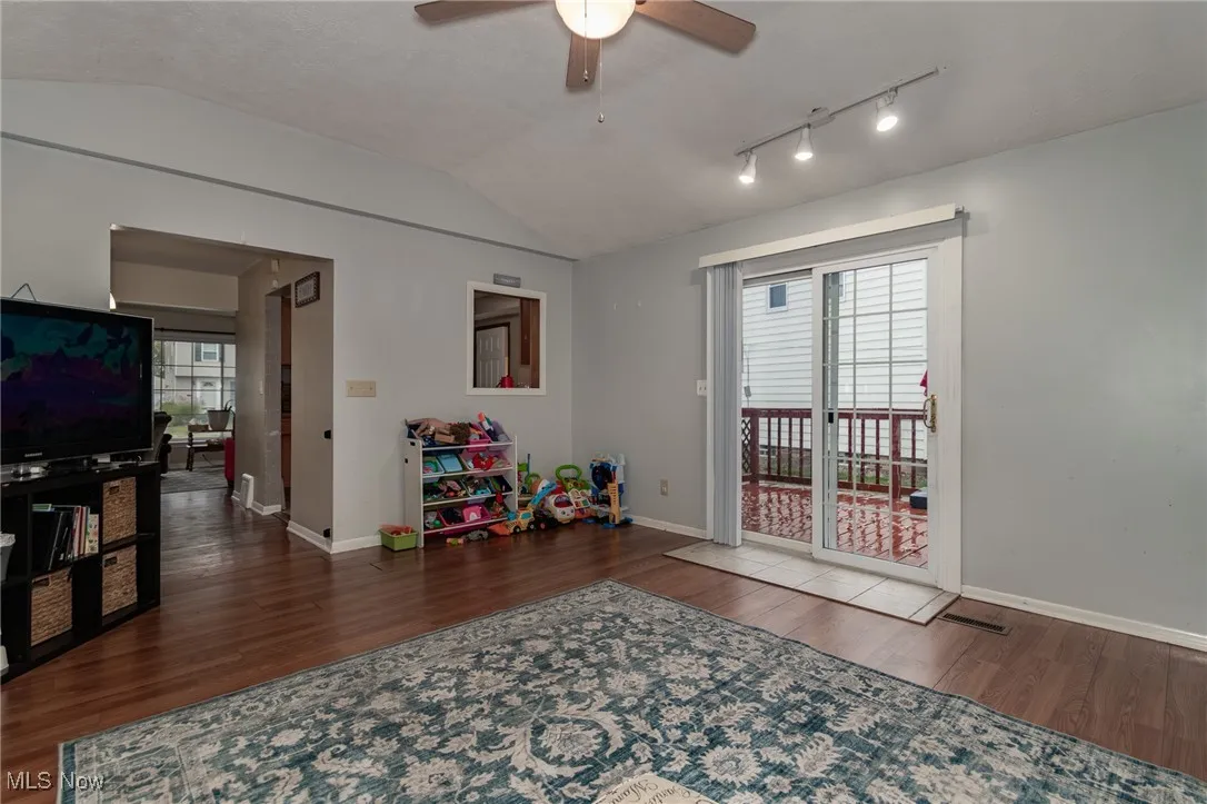 Playroom with lofted ceiling, plenty of natural light, dark wood-type flooring, a ceiling fan, and track lighting