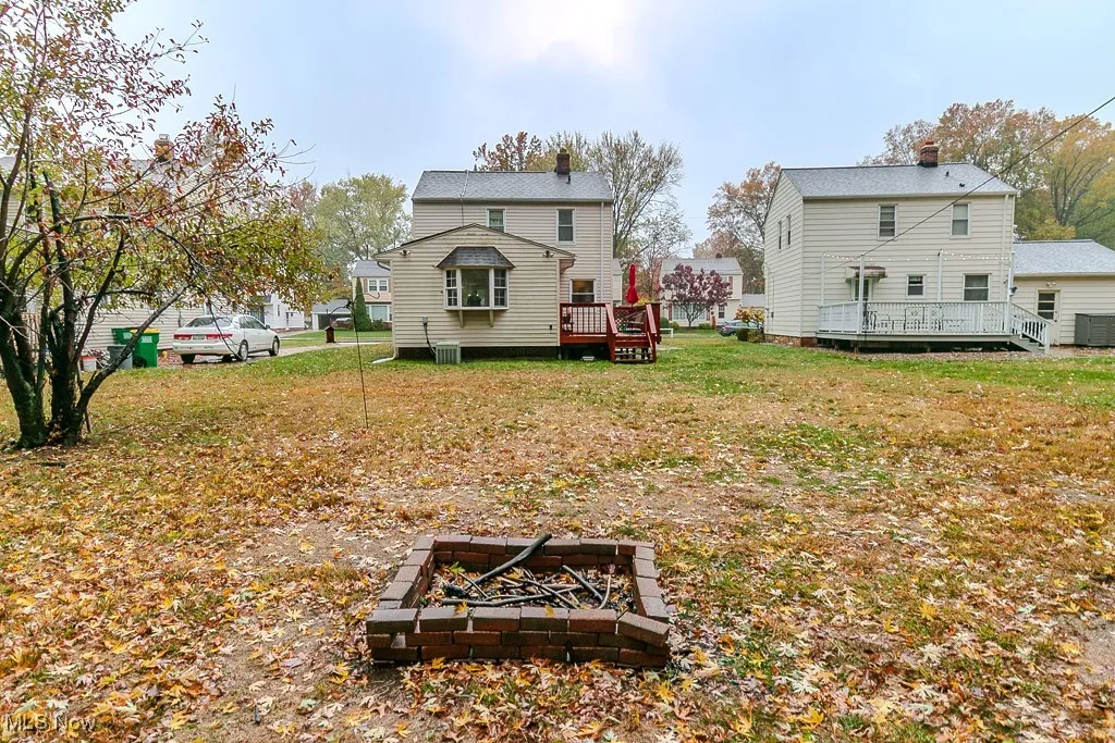 Back of property with a deck, a fire pit, and a yard