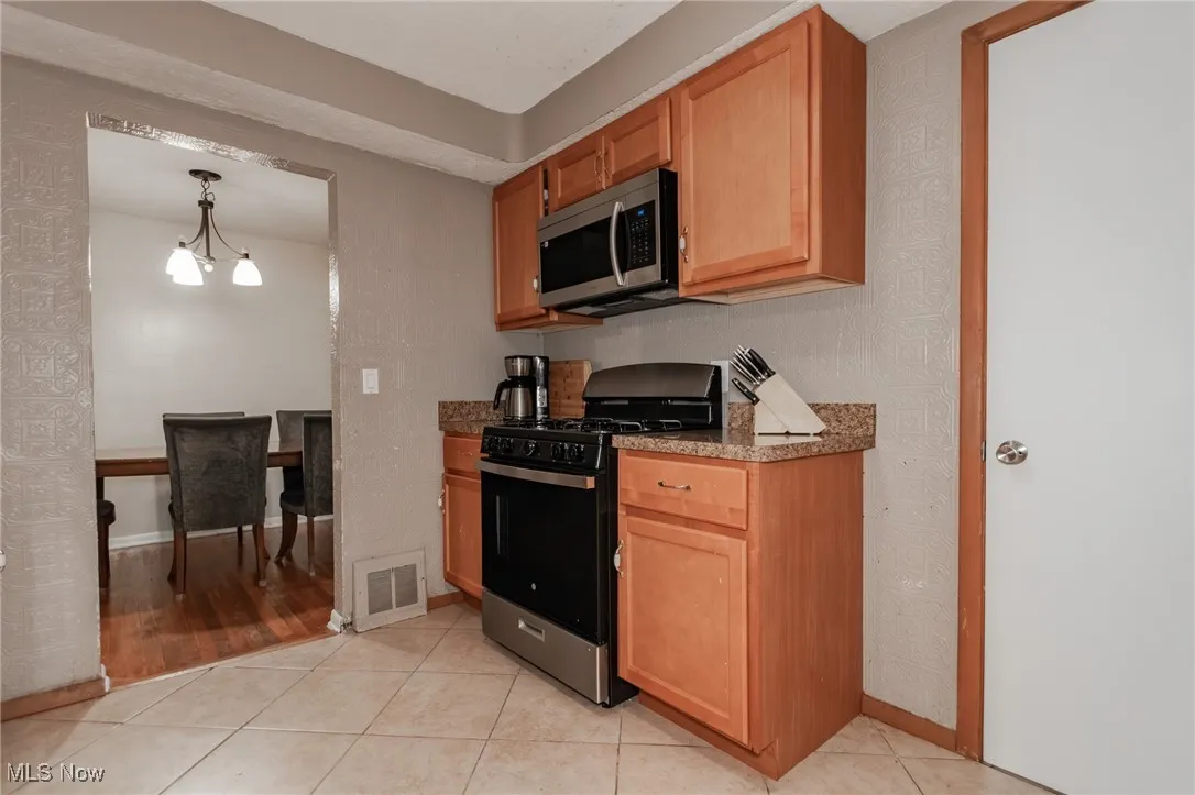 Kitchen featuring stainless steel appliances, light tile patterned flooring, decorative light fixtures, and a chandelier