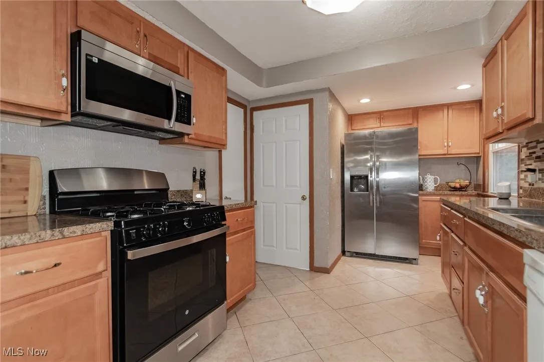 Kitchen with decorative backsplash, stainless steel appliances, light tile patterned floors, and recessed lighting