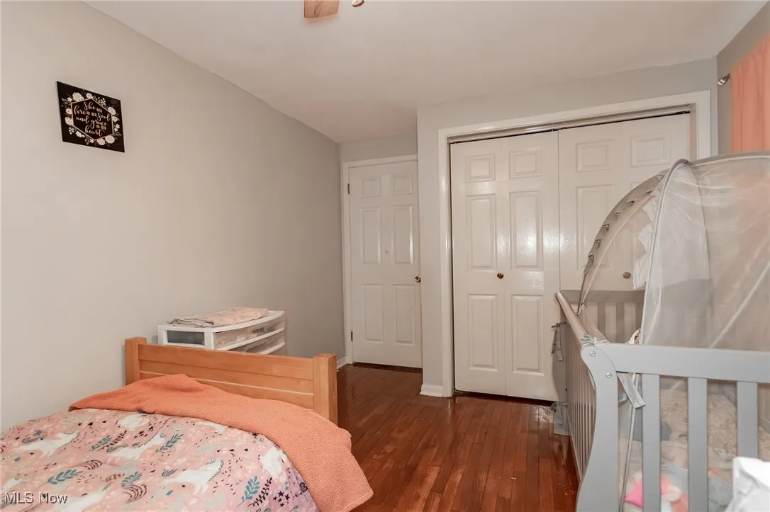 Bedroom with dark wood finished floors, a closet, and ceiling fan