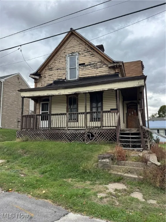 View of front of property with covered porch and a front yard