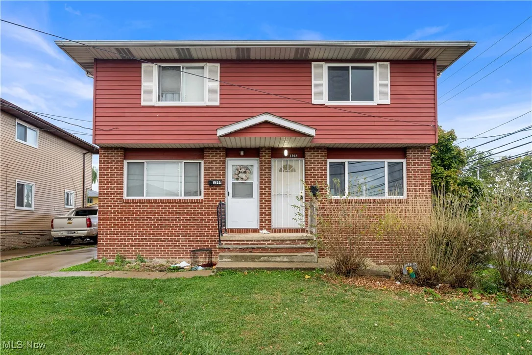 Colonial home with brick siding and a front yard