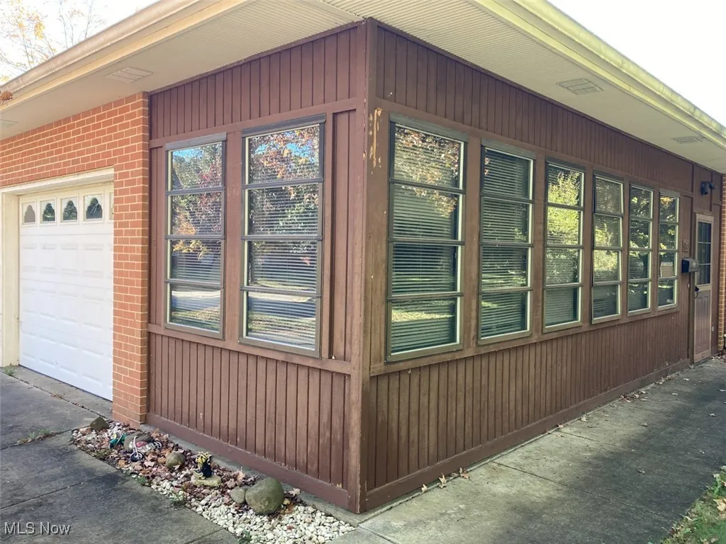 View of side of home with brick siding, an attached garage, and driveway