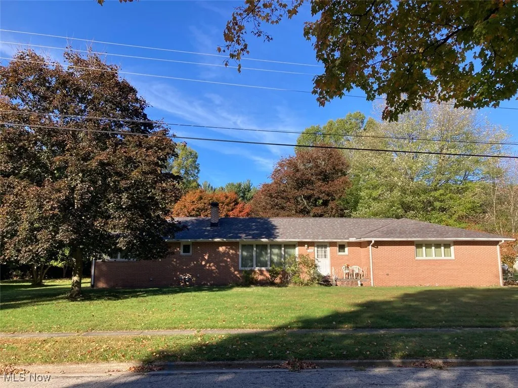 Ranch-style house with a front lawn, brick siding, and a chimney