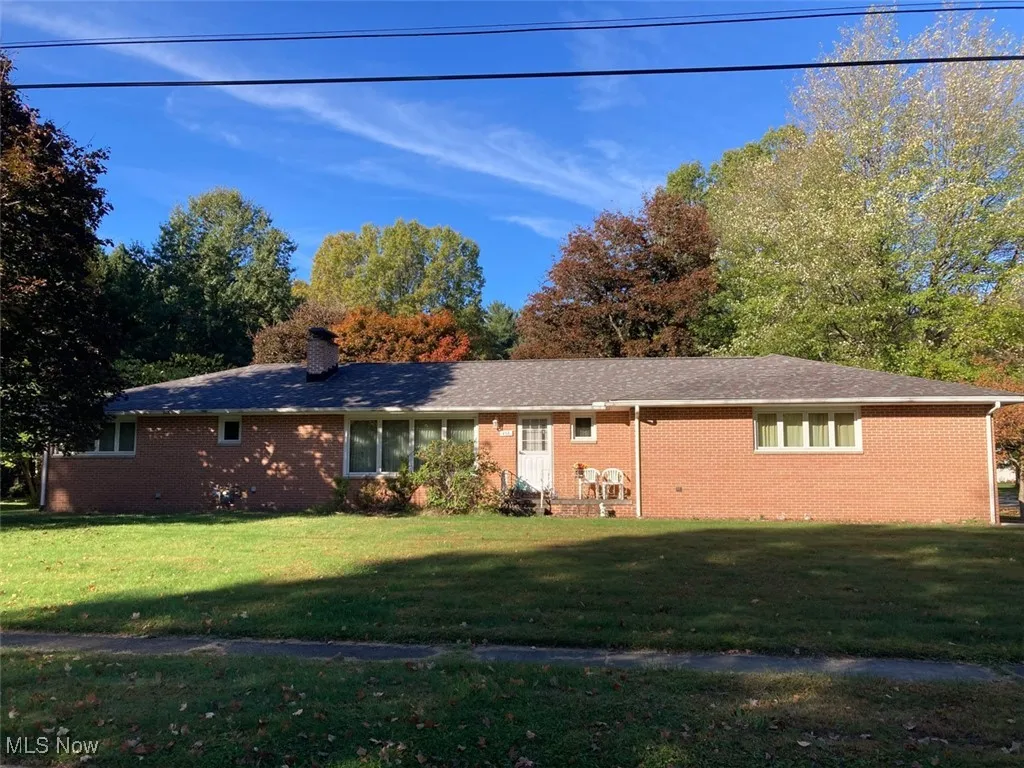 Ranch-style house featuring a front yard, brick siding, and a chimney