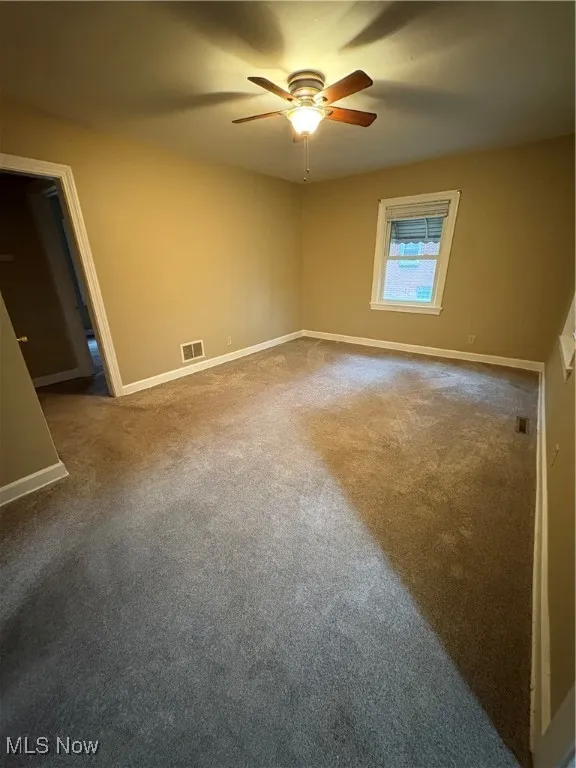 Carpeted spare room featuring baseboards
