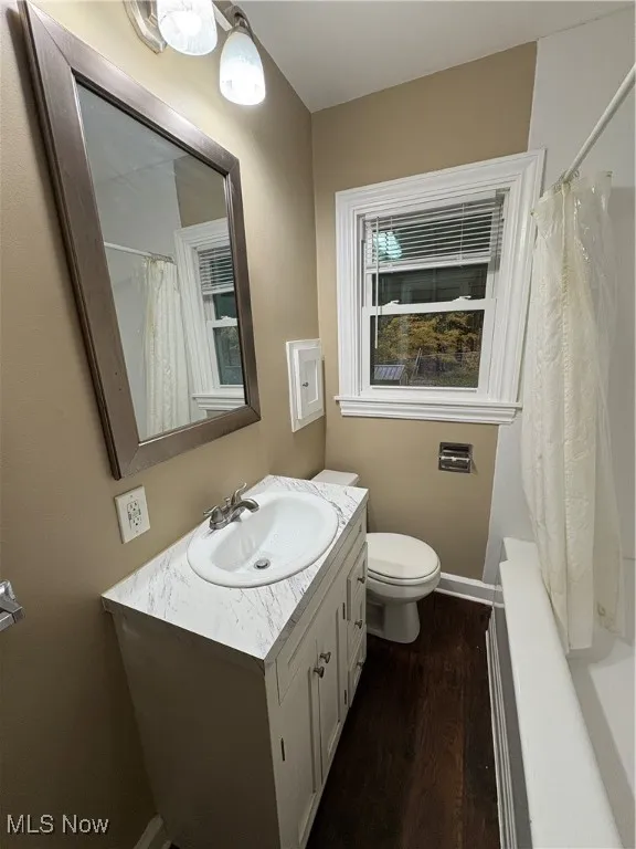 Bathroom with dark wood-style flooring, vanity, and shower / bath combo