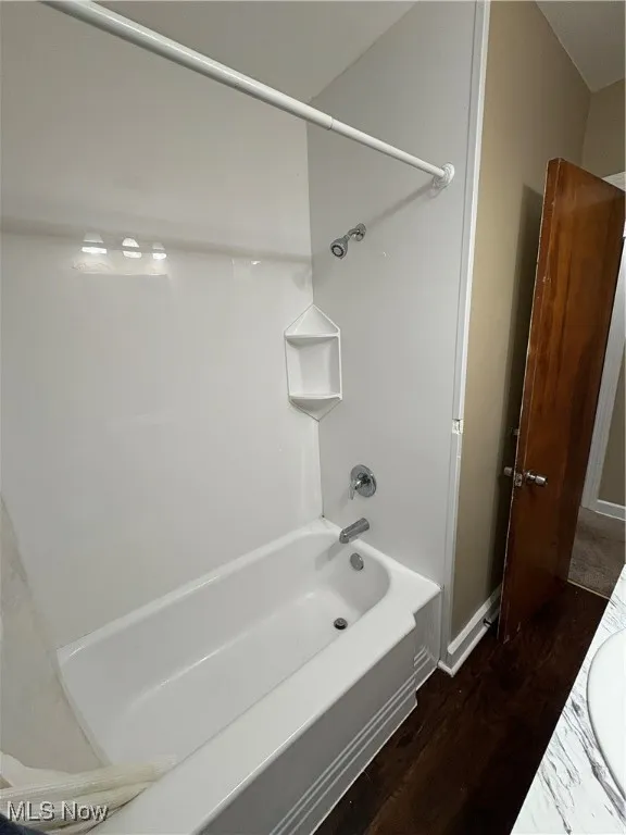 Bathroom featuring dark wood-style floors, shower / bathtub combination, and vanity