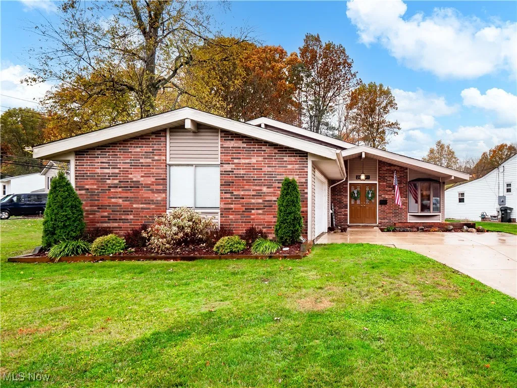 Mid-century home with a front yard, brick siding, and driveway