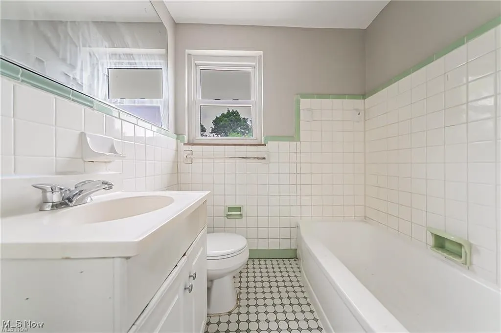 Bathroom with vanity, a tub, tile walls, and light tile patterned floors