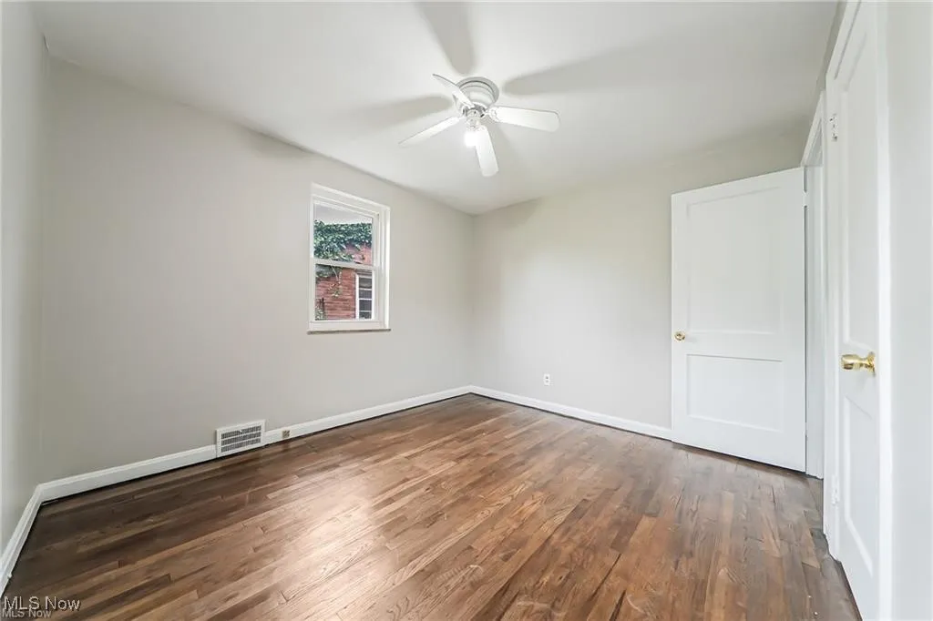 Spare room featuring dark wood-type flooring and ceiling fan