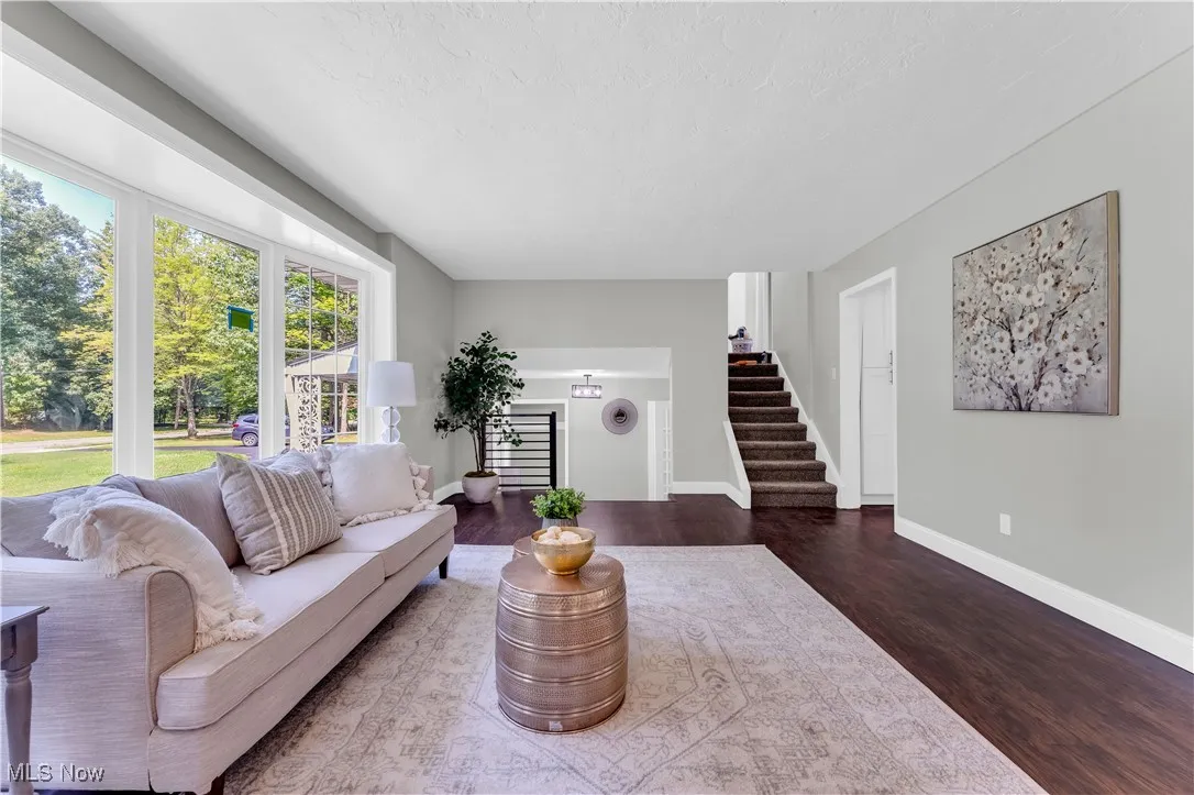 Living room featuring dark wood-style flooring, a textured ceiling, and stairs
