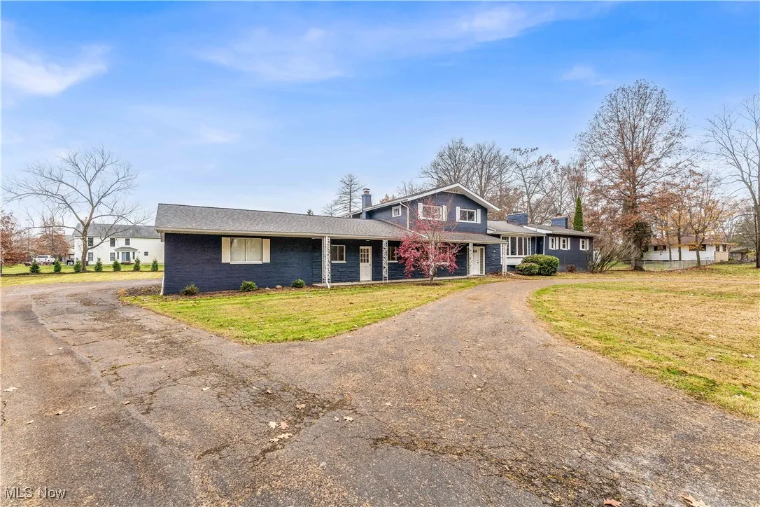 Tri-level home with asphalt driveway, a front yard, a porch, brick siding, and a chimney