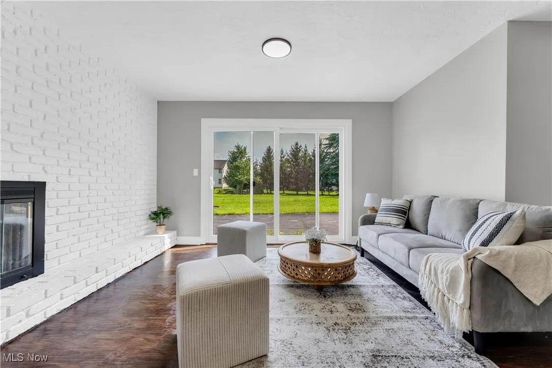 Living area featuring dark wood-style floors, a fireplace, and brick wall