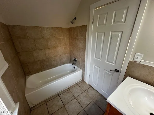 Bathroom with vanity, dark tile patterned flooring, and shower / washtub combination